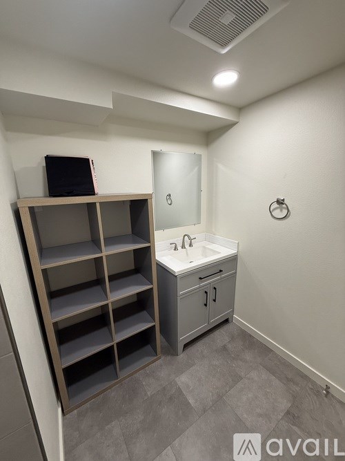 A bathroom with a sink, mirror, and shelves.