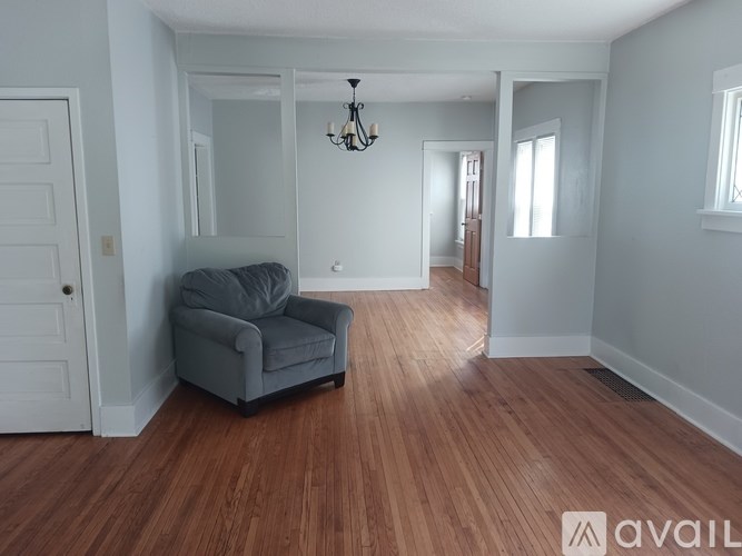 A room with a grey couch and wooden flooring.