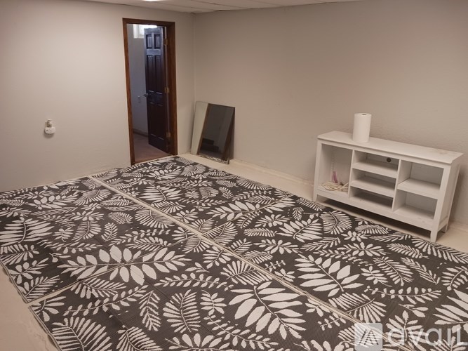 A room with a patterned carpet and a white shelf unit.