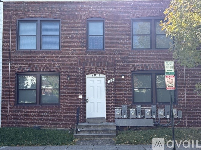 A red brick building with a white door and a sign on the right.