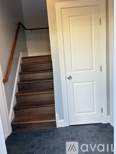A white door is on the right of a staircase.