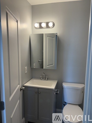 A bathroom with a toilet, sink, and mirror.