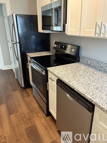 A kitchen with a black fridge, microwave, and stove top oven.