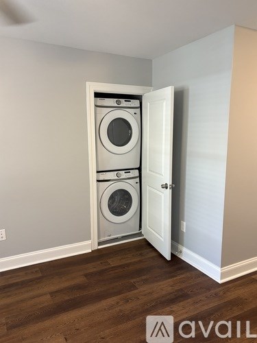 A washer and dryer are built into a wall in a room with wood flooring.