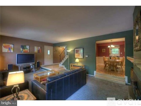 A living room with a couch, television, and a staircase.