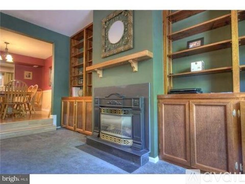 A living room with a fireplace and wooden furniture.