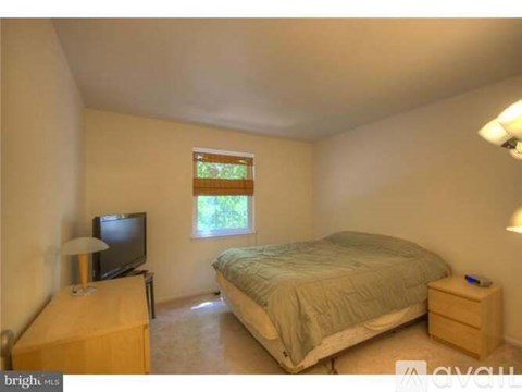 A bedroom with a bed, a television, and a window with blinds.