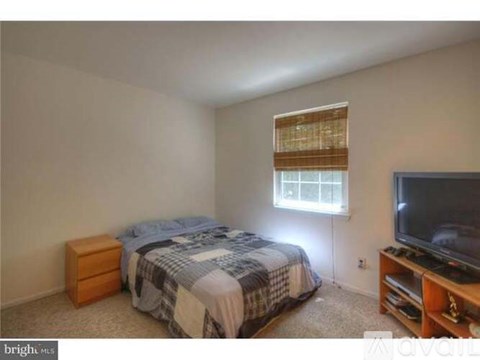 A bedroom with a bed, dresser, and television.
