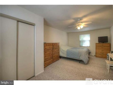 A bedroom with a bed, dresser, and ceiling fan.
