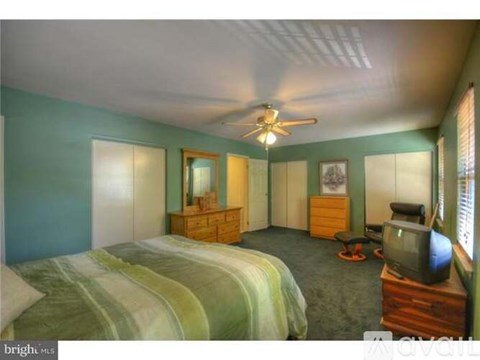A bedroom with a bed, dresser, and television.
