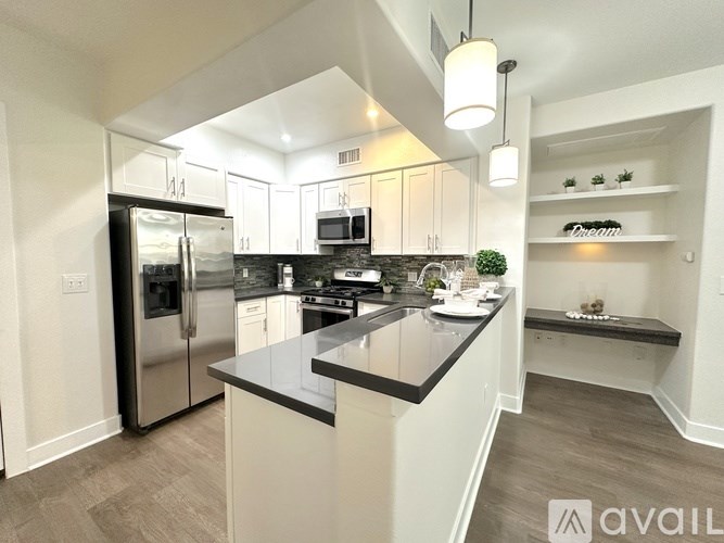 A modern kitchen with a black countertop and stainless steel appliances.