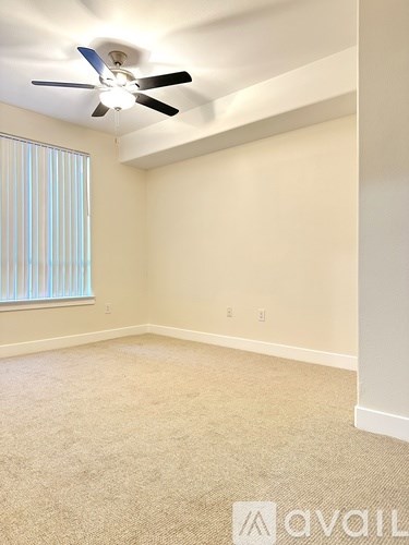 A room with a ceiling fan and carpeted floor.