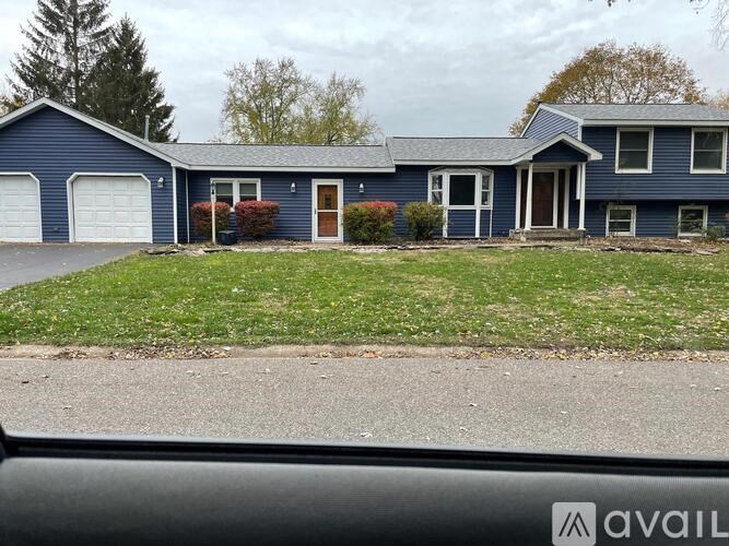 A blue house with a white garage door and a brown door.