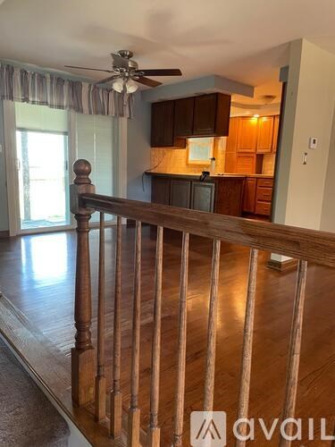 A wooden staircase with a railing leads to a kitchen area.