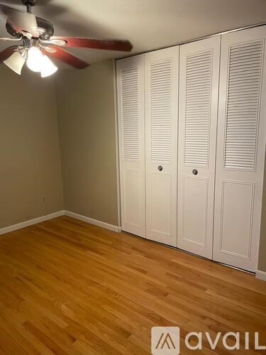 A room with a ceiling fan and three white doors.