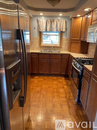 A kitchen with wooden cabinets and a stainless steel refrigerator.