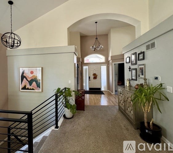 A hallway with a carpeted floor, a black railing, and a painting on the wall.