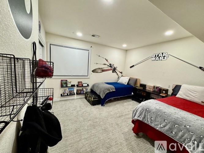 A room with two beds, one with a grey and red comforter and the other with a blue and grey comforter.