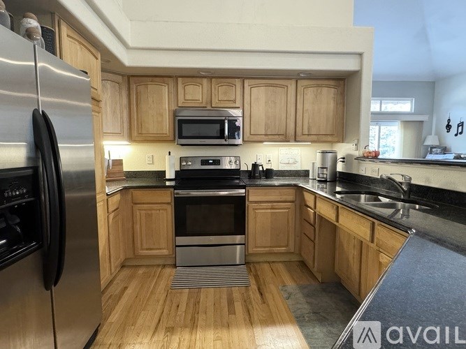 A kitchen with wooden cabinets and a stainless steel refrigerator.