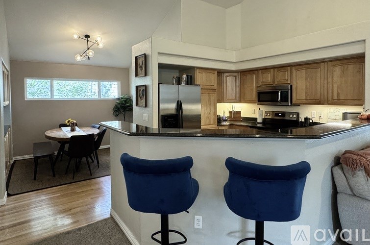 A kitchen with a table and two blue chairs.