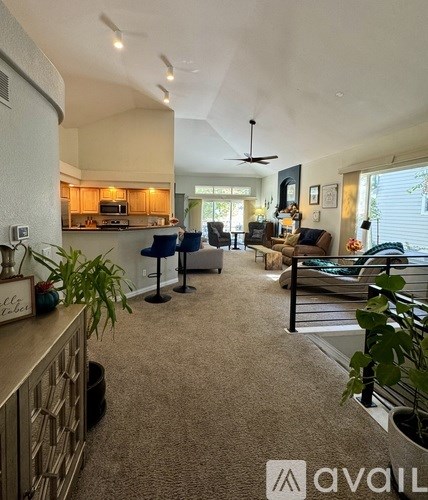 A living room with a kitchen in the background and a dining table in the middle.