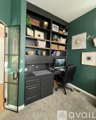A room with a green wall and a black chair.