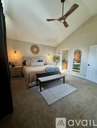 A bedroom with a bed, a bench, and a ceiling fan.