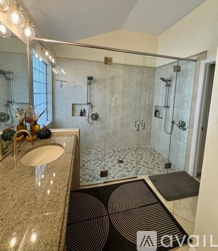 A bathroom with a sink, mirror, and shower.