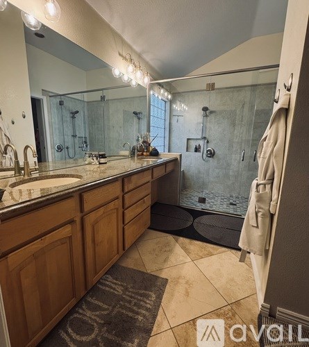 A bathroom with a sink, mirror, and shower.