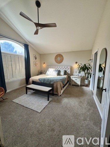A bedroom with a bed, nightstand, and a ceiling fan.