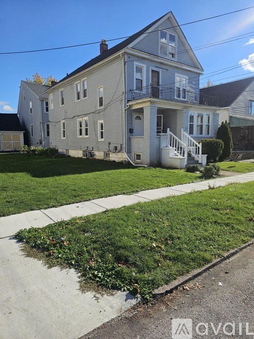 A two-story house with a grey facade and a balcony on the second floor.
