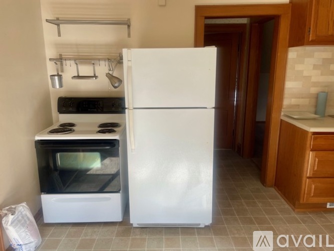 A white refrigerator stands in a kitchen next to a stove.