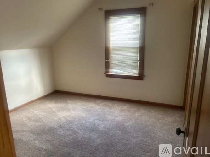 A room with a carpeted floor and a window with blinds.