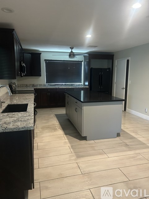 A kitchen with a black fridge and a white island.
