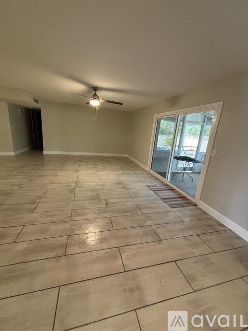 A spacious room with a ceiling fan and tiled flooring.