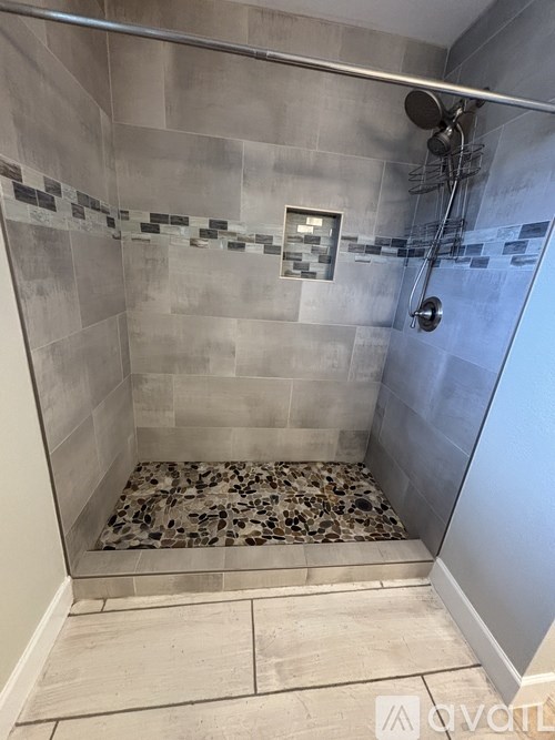 A shower with a glass door and a tiled floor.