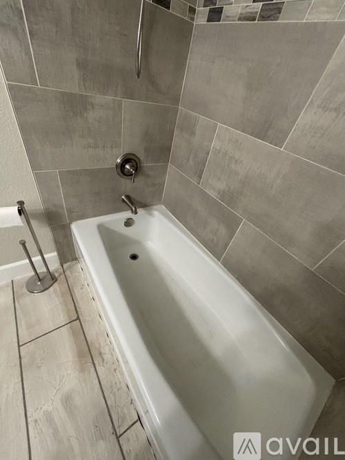 A white bathtub with a shower head and a shower hose.