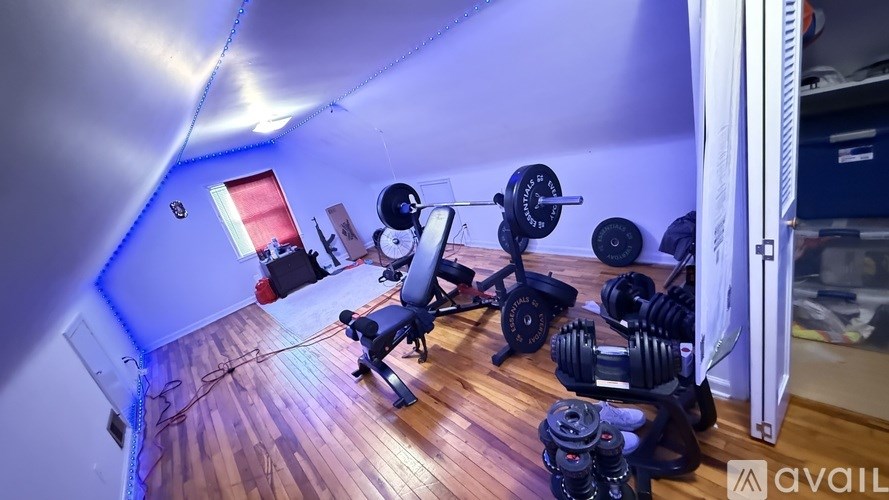 A room with a wooden floor and a variety of exercise equipment.