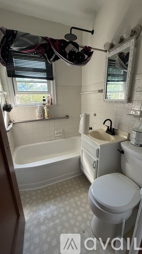 A white toilet is in a bathroom with a white tub and sink.
