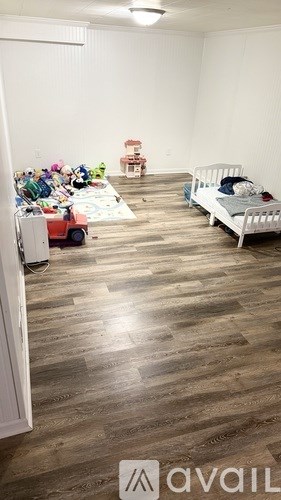 A room with a bed, a toy truck, and a pile of toys on the floor.