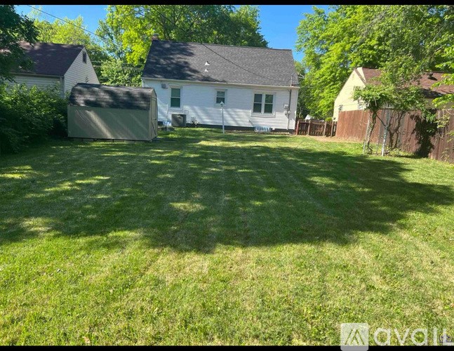 A backyard with a white house and a green lawn.