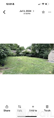 A grassy area with trees and a building in the background.