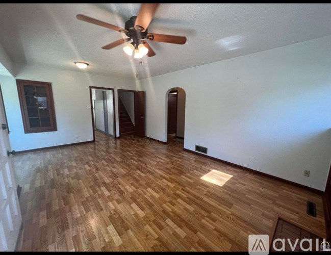 A room with wooden flooring and a ceiling fan.