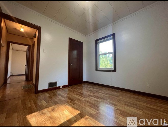 A room with wooden floors and a window showing greenery outside.