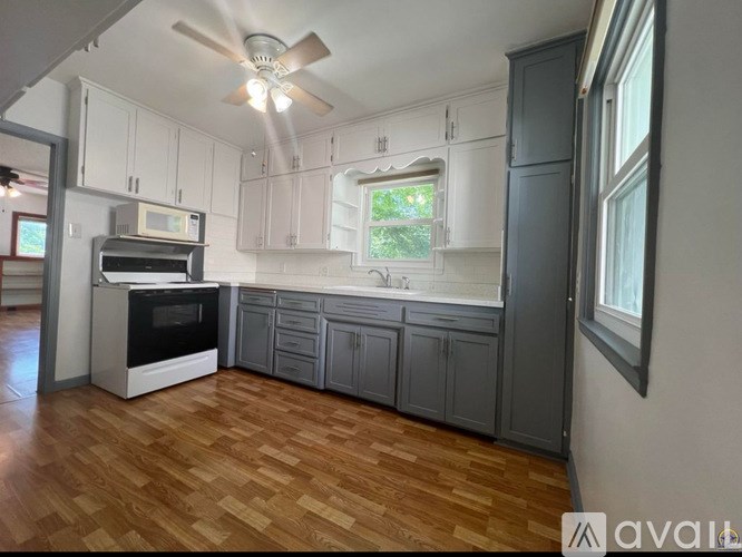 A kitchen with wooden floors and a ceiling fan.