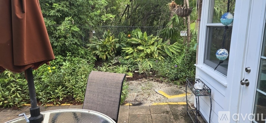 A patio with a table, chair, and umbrella.