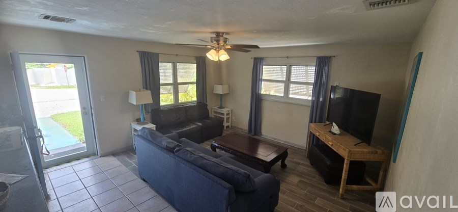 A living room with a couch, a coffee table, a television, and a ceiling fan.