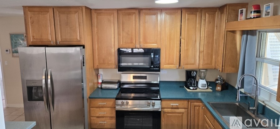 A kitchen with wooden cabinets and a stainless steel refrigerator.