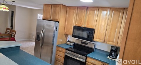 A kitchen with wooden cabinets and a stainless steel refrigerator.