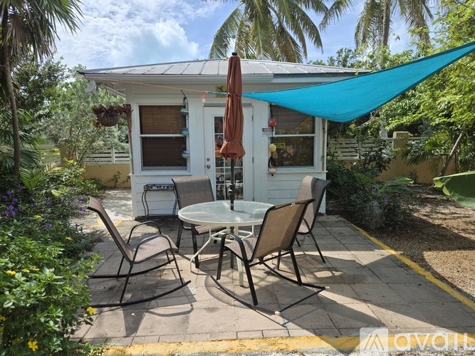 A patio with a table and chairs under a blue shade sail.